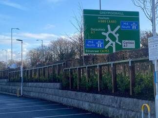 Road sign indicating directions to a roundabout and nearby facilities in Carlisle, Cumbria.